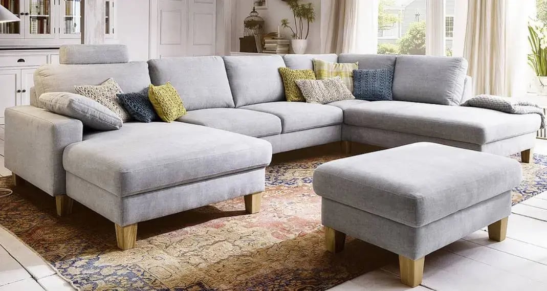 Auf dem Bild ist ein graues Sofa mit bunten Kissen zu sehen.